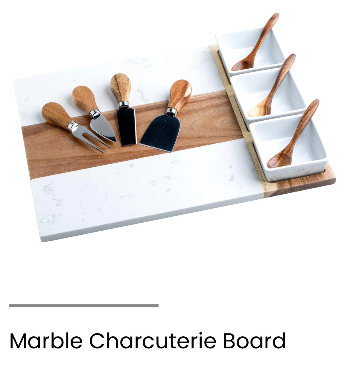 A marble charcuterie board with a white and light gray stone surface and a natural wood center strip, shown with wooden-handled cheese knives, a spreader, and three small white square serving dishes with wooden spoons. Text below reads 'Marble Charcuterie Board'.
