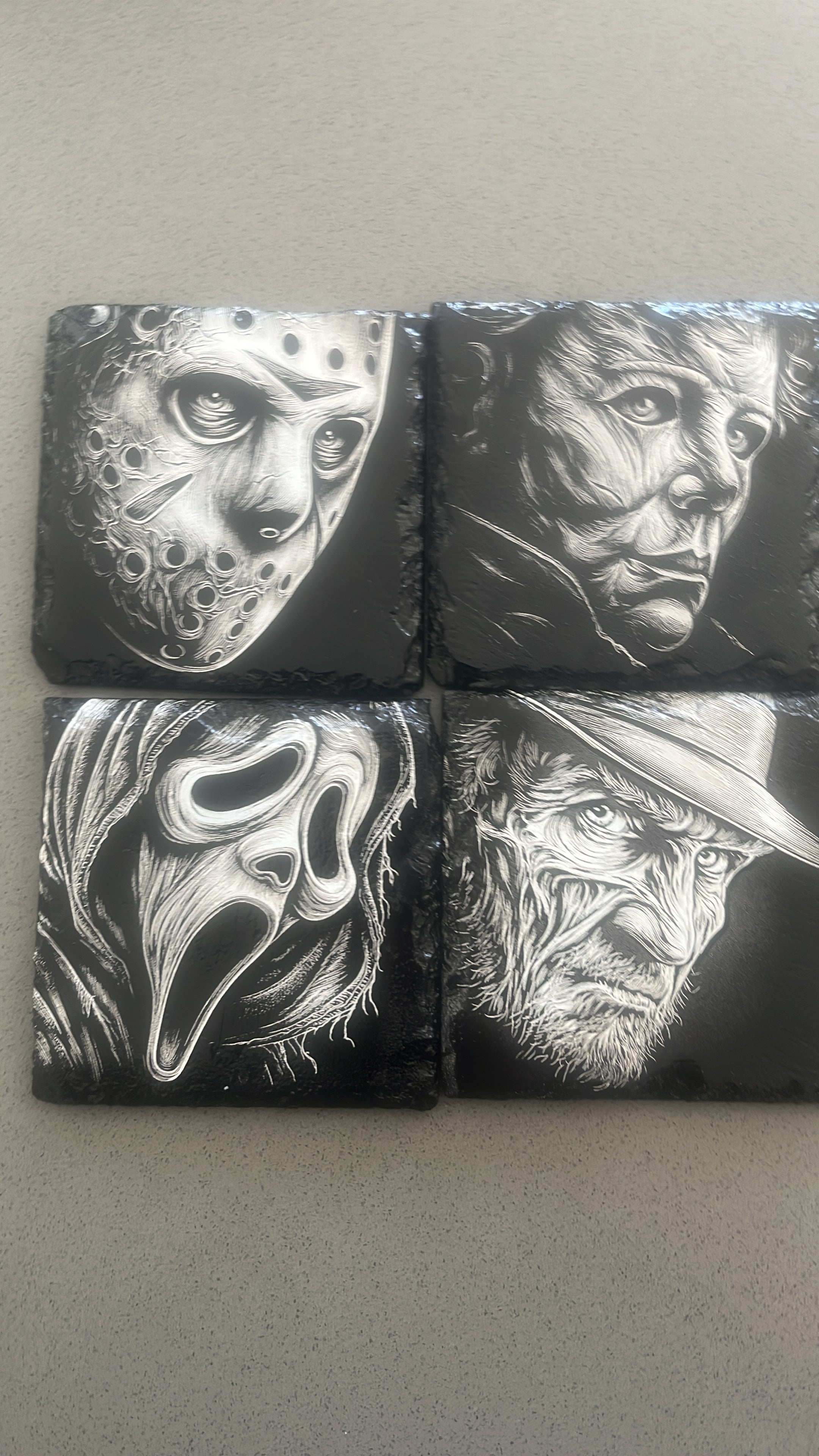 Four square black coasters featuring detailed black and white illustrations of horror movie villains: Jason Voorhees, Michael Myers, Sally the Screaming Mask, and Freddy Krueger.