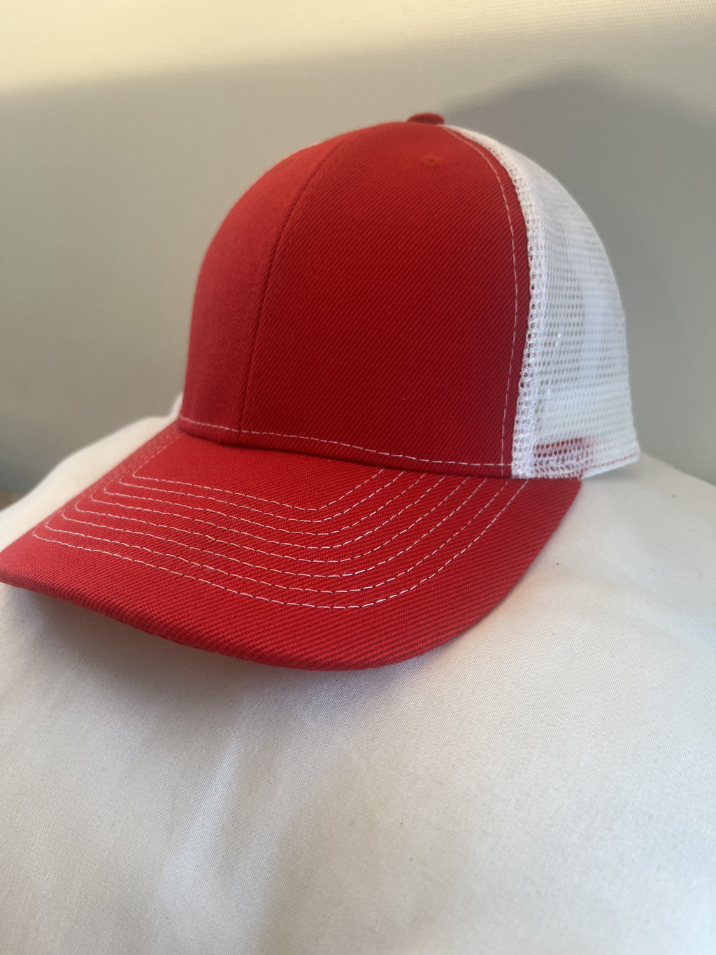 A red and white trucker-style baseball cap with a solid red front panels and brim, and white mesh back panels.