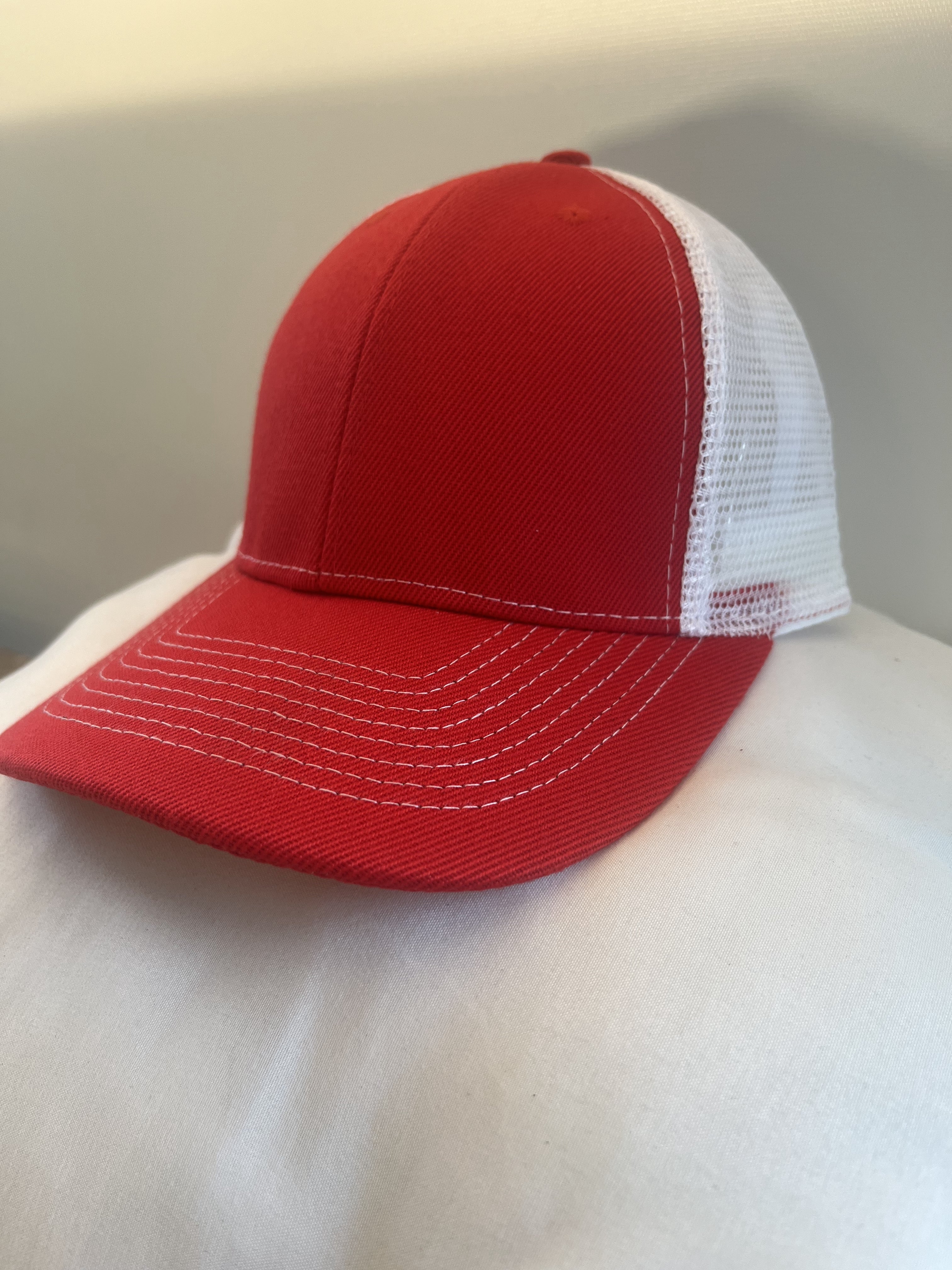 A red and white trucker-style baseball cap with a solid red front panels and brim, and white mesh back panels.